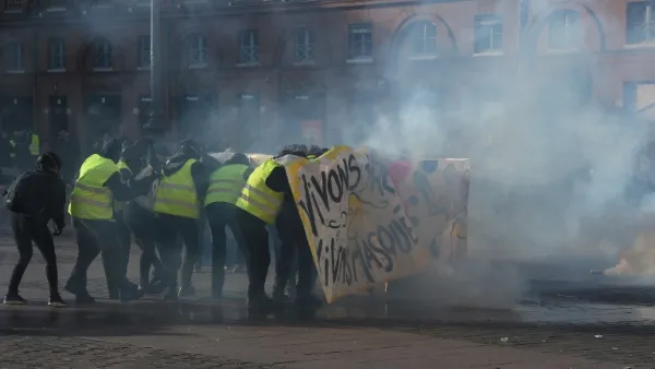 Protesters hide behind a banner amid tear gas smoke during a demonstration in Toulouse, southern France, on February 9, 2019. (AFP/ File)