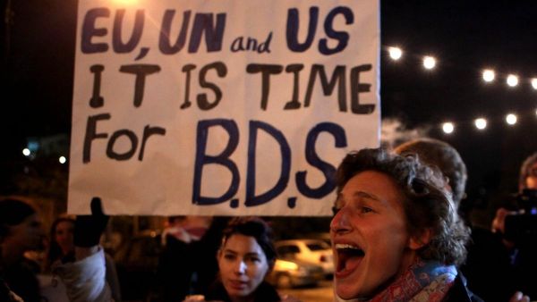 Demonstrators hold a placard urging the international community to support the Boycott, Divestment, and Sanctions (BDS) campaign. (AFP/ File Photo)
