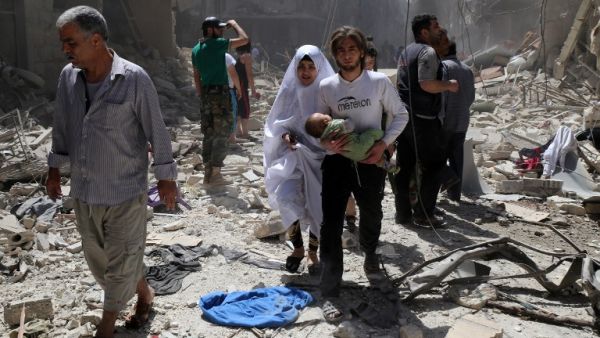 A Syrian family walks amid the rubble of destroyed buildings following a reported airstrike on April 28, 2016 in the Bustan al-Qasr rebel-held district of the northern Syrian city of Aleppo. (AFP/Baraa al-Halabi)