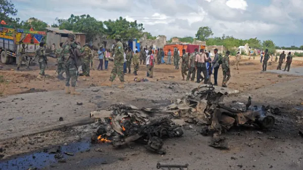 Soldiers patrol around the wreckage of a suicide car bomber that smashed into a pickup truck carrying security officers in Mogadishu. (AFP/File)