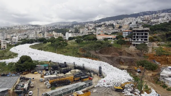 Trucks are seen next to piles of garbage in Jdeideh, a Beirut suburb, ahead of moving it to the country's largest landfill of Naameh, just south of the Lebanese capital, on March 20, 2016. (AFP/Anwar Amro)