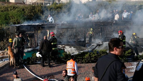 Israeli security forces and emergency services gather around a burnt-out bus following an explosion by IED (improvised explosive device). (AFP/File) 