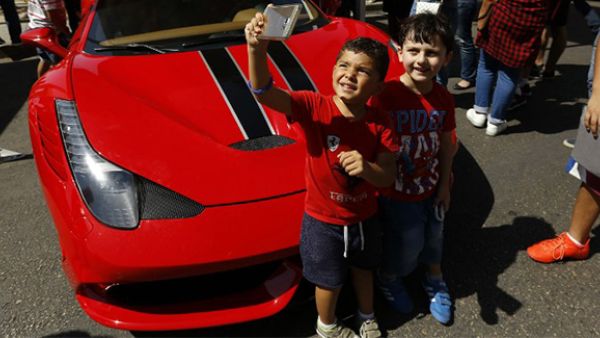 Two children pose for a picture next to a Ferrari during the 2016 Beirut Grand Prix, a Supercar racing event for non-professional drivers, in the capital's Ramlet al-Baida neighberhood.(AFP/File)
