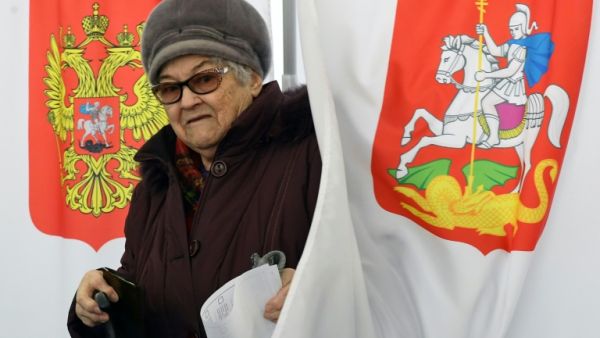 An elderly woman walks out of a voting booth at a polling station during Russia's presidential election (AFP/File Photo)