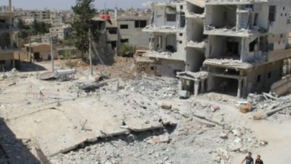 Syrian men walk past the rubble of buildings recently destroyed in airstrikes by government forces on the rebel-held neighborhood of Tareeq al-Saad in Daraa city, on August 26, 2015. (AFP/File)