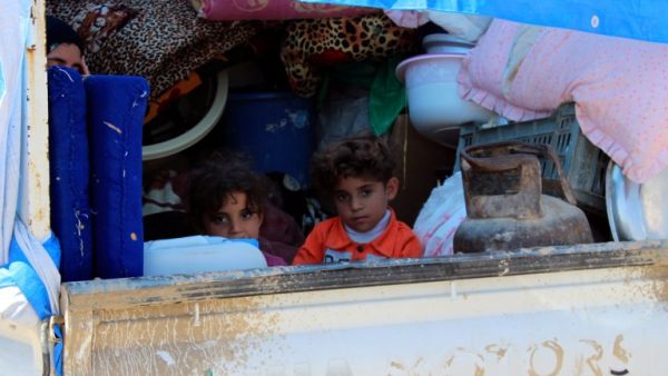 A displaced Iraqi family sit in the back of a truck in a queue for security checks as some 250 families return to their homes in Iraq's Anbar province on March 29, 2016. (AFP/Moadh al-Dulaimi)