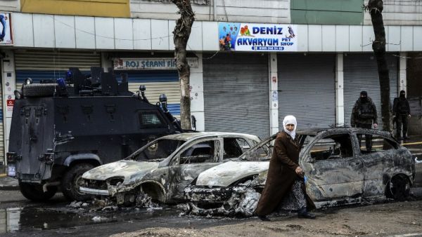 People walk past destroyed vehicles as they leave their houses during clashes in central Diyarbakir on March 15, 2016. (AFP/Ilyas Akengin)