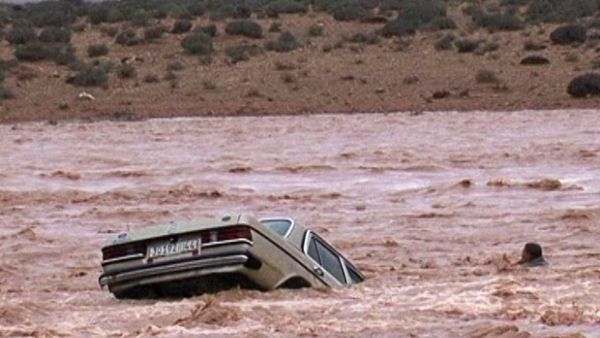 A man is separated from his car as flash floods sweep the vehicle from a road in Ouarzazate, southern Morocco. (AFP/File)