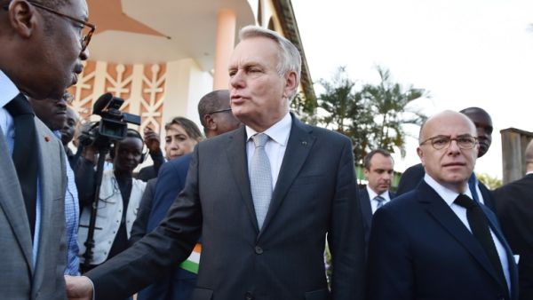 French Minister of Foreign Affairs Jean-Marc Ayrault (C) and French Interior Minister Bernard Cazeneuve (R) walk in front of one of the sites of the March 12 attack that killed 18 people in Grand Bassam. 