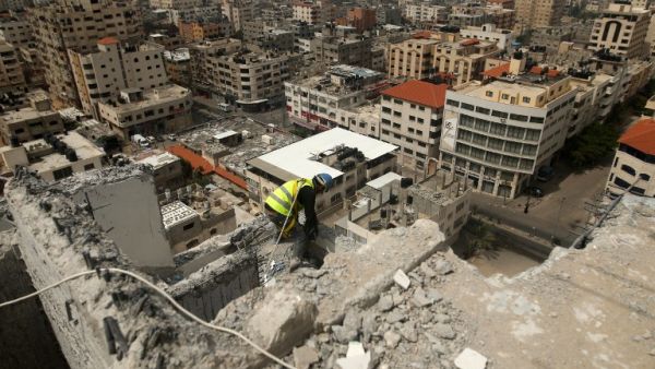 A Palestinian worker removes debris from buildings which were destroyed during the 50-day war between Israel and Hamas militants in the summer of 2014, in Gaza City, on April 5, 2016. (AFP/Mohammed Abed)