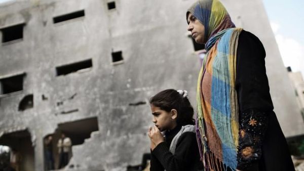فلسطينية وابنتها تنظران الى منزل ال الدلو الذي قصفته اسرائيل خلال العدوان /أ.ف.ب