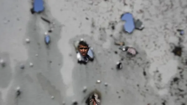 فلسطيني ينظر من خلال الحفر التي احدثتها غارة جوية اسرائيلية في جدران منزله في مخيم جباليا للاجئين الفلسطينيين في غزة/أ.ف.ب