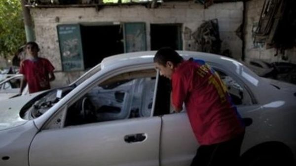شابان فلسطينيان يعملان في ورشة لتصليح السيارات في غزة