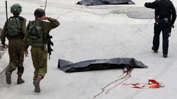 Israeli soldiers in Hebron near the bodies of two Palestinians who were killed after stabbing an IDF soldier. (AFP/File)