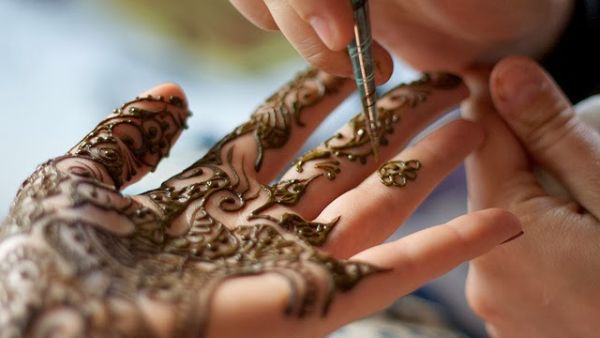 A woman getting a henna ink design applied to her hand. (Shutterstock)