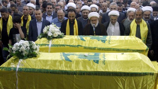 Members of Lebanon's Shiite movement Hezbollah pray in front the coffins of Shiite militants Khodr Aladdine and Hassan Bajouk during their funeral in the capital Beirut on May 8, 2015, after they were killed in combat alongside Syrian government forces in the Qalamoun region. (AFP/File) 
