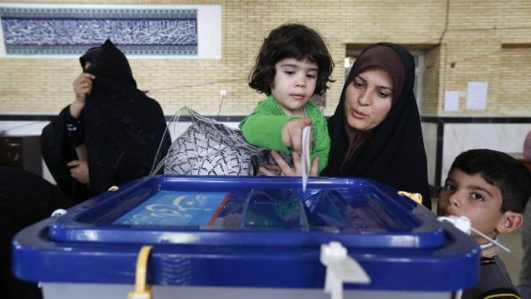 An Iranian woman holds a child to help her cast her ballot as she votes in the second round of parliamentary elections in Robat Karim, some 40 kms southwest of Tehran, on April 29, 2016. (AFP/Atta Kenare)