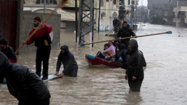Palestinian civil defense volunteers help people to travel across flood waters in Gaza City following rain storms for the past few days, on December 14, 2013. [Getty Images]