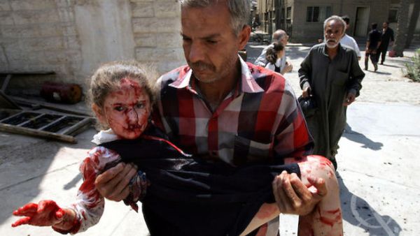 Man carries child from school bombing rubble. [photoshelter]