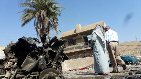 Iraqis look at the remains of a vehicle following an explosion on October 27, 2013, in the Mashtal district of the capital Baghdad. (Image credit: AFP)