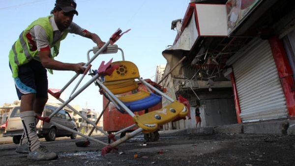 An Iraqi worker removes chairs as he cleans the site of a car bomb attack. (Image credit: AFP)