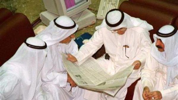 مجموعة من الكويتيين يستعرضون صحيفة داخل البورصة بالكويت العاصمة
