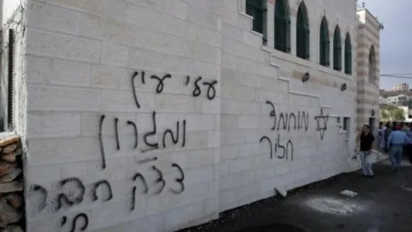 فلسطيني يتكلم على الهاتف في 5 ايلول/سبتمبر الى جانب كتابات بالعبرية على جدار مسجد في الضفة الغربية
