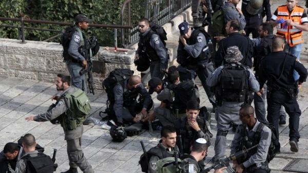 Israeli border guards give first aid to an injured police officer, who was stabbed along with another officer by a Palestinian, on October 10, 2015. (AFP/Gali Tibbon)