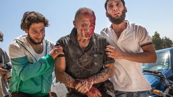 Syrian men rush a heavily wounded man to hospital in Saraqeb in northwestern Syria after a barrel bomb dropped by an air force helicopter exploded less than 10 meters away from his car (AFP/DANIEL LEAL-OLIVAS)