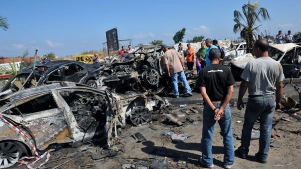 LEBANON, Tripoli : Lebanese look at burnt vehicles on August 24, 2013 on the site of a bombing outside Al-Taqwa mosque the day before in the northern city of Tripoli. AFP PHOTO IBRAHIM CHALHOUB