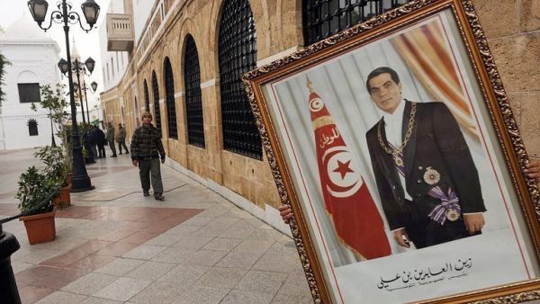 عامل يزيل صورة للرئيس التونسي المخلوع زين العابدين بن علي من مكتب رئيس الوزراء في تونس
