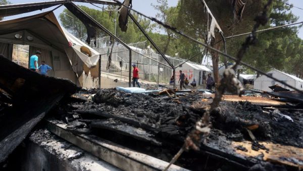 A man walks through the burned tents after a riot at a Lesbos detention center. (AFP/Stringer)