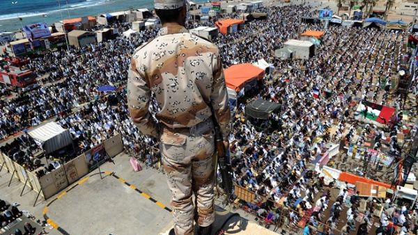 A Libyan rebel stands guard on top of a roof overlooking thousands performing noon prayers in Revolution Square in Benghazi on May 13, 2011. (Saeed Khan/ AFP)