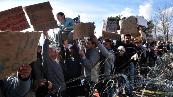 Men demonstrate near a barbed wire fence on 27 February, 2016 at the Idomeni camp on Greece's northern border with Macedonia, demanding that the Macedonian authorities let them in. (AFP/Sakis Mitrolidis)
