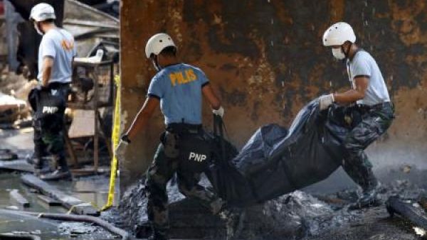 شرطيان يحملان جثة احد ضحايا حريق بمصنع في مانيلا يوم الارربعاء
