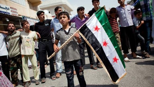 In August this year a boy holds a pre-Baath Syrian flag, that was adopted by the Syrian revolution during the uprising. (AFP PHOTO / ACHILLEAS ZAVALLIS)