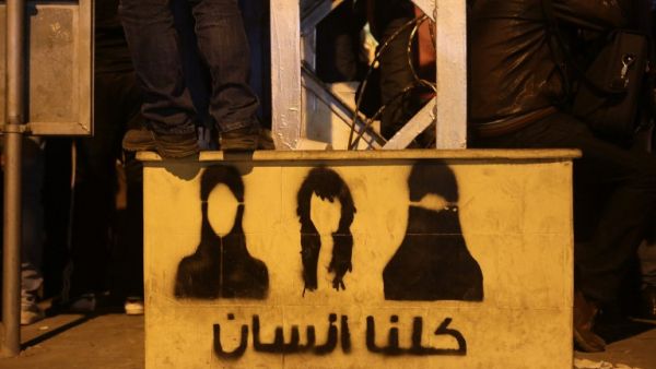 An opposition supporter stands on top of a step painted with graffiti and Arabic writing that reads, "We are all people" during a demonstration outside Egyptian presidential palace against Egyptian President Mohamed Morsi. (AFP PHOTO/PATRICK BAZ)