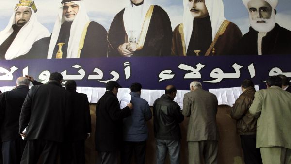 Jordanian polling station officials read lists explaining the distribution of ballot boxes in Amman on Tuesday on the eve of the general election. (Khalil Mazrawwi/AFP)