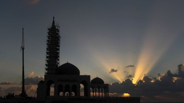 A mosque under construction is silhouetted as the sun sets along the seafront in Gaza City. (AFP Photo / MAHMUD HAMS)