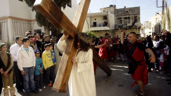 A Christian man holds a large wooden cross as Lebanese Christians reenact the crucifixion of Jesus Christ during the Good Friday procession in the southern village of Qraiyeh. (AFP PHOTO/MAHMOUD ZAYAT)