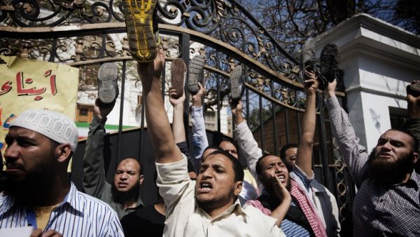 Egyptian protestors raise their shoes as they shout political and religious slogans outside the Iranian ambassador's residence in Cairo. (AFP PHOTO/GIANLUIGI GUERCIA)