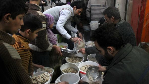 Syrian youths gather to receive aid food in the northern Syrian city of Aleppo on January 14, 2014. [AFP]
