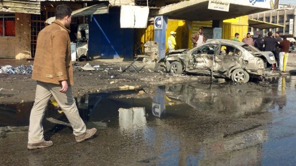 An Iraqi man walks past the site of a car bomb in central Baghdad, on January 15, 2014. [AFP]
