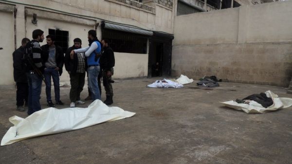 Rebel fighters talk near the bodies of the victims of a suicide bombing allegedly carried by al-Qaeda-linked group Islamic State of Iraq and the Levant's (ISIL) near the headquarters of the Army of the Mujahideen. [AFP]