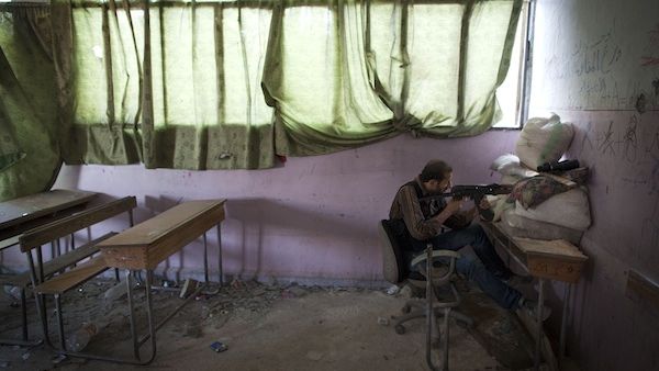 A rebel fighter aims his weapon to Syrian government forces' positions inside a destroyed school in the Izaa district of Aleppo, on July 14, 2013. (AFP)