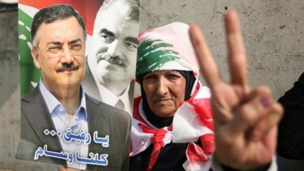 One of the mourners holds a picture of Hassan (left) with Rafiq Hariri (right): (picture courtesy of Hasan Shaaban/Daily Star)