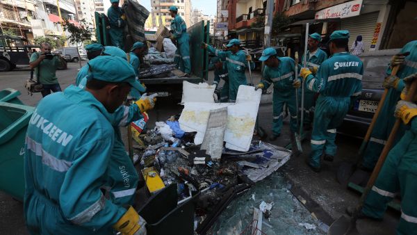 Municipal workers clean up following a car bomb attack the previous day that killed at least 27 people in a Beirut stronghold of Shiite group Hezbollah, which backs Syria's embattled president (AFP/STR)