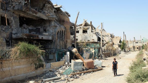 A Syrian rebel walks past buildings destroyed during fighting with pro-government forces along a street in a residential neighborhood of Syria's eastern town of Deir Ezzor (AFP/ABO SHUJA)