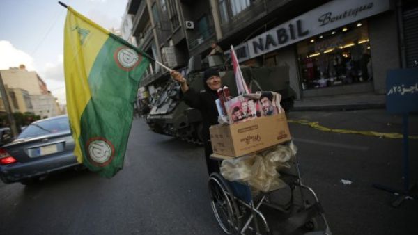 A Lebanese Shiite woman waves a Hezbollah and Amal movements flag as she pushes a cart past a Lebanese army forces checkpoint in the southern suburb of Beirut on September 23, 2013. Shells fired from Syria, where Hezbollah are fighting, hit northern Lebanese towns on Wednesday. (AFP)