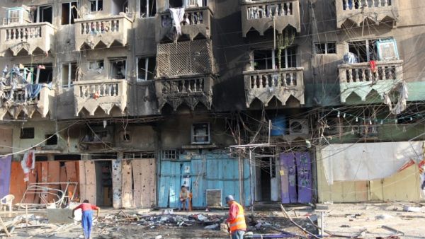 An Iraqi worker cleans the pavement on August 11, 2013 on the scene of a car bomb attack that occured the day before in the northern Baghdad neighbourhood of Shaab. (AFP)